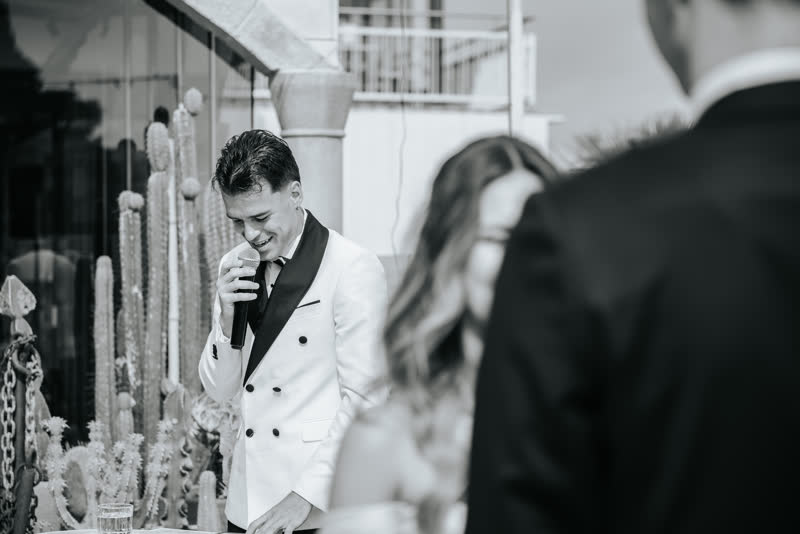 Black and white photograph of Vova leading the ceremony beside the couple