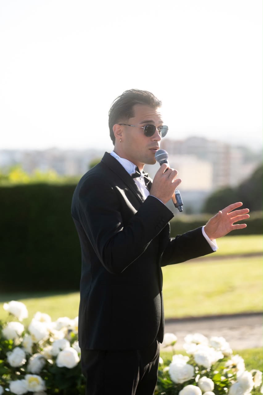 Vova speaking into a microphone during an outdoor ceremony